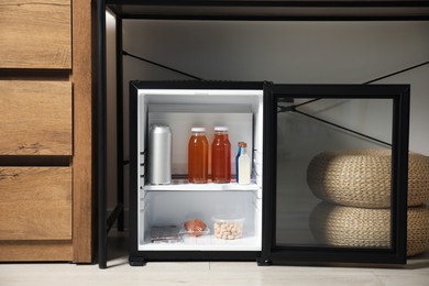 Mini refrigerator with different drinks and snacks indoors