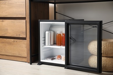 Mini refrigerator with different drinks and snacks indoors