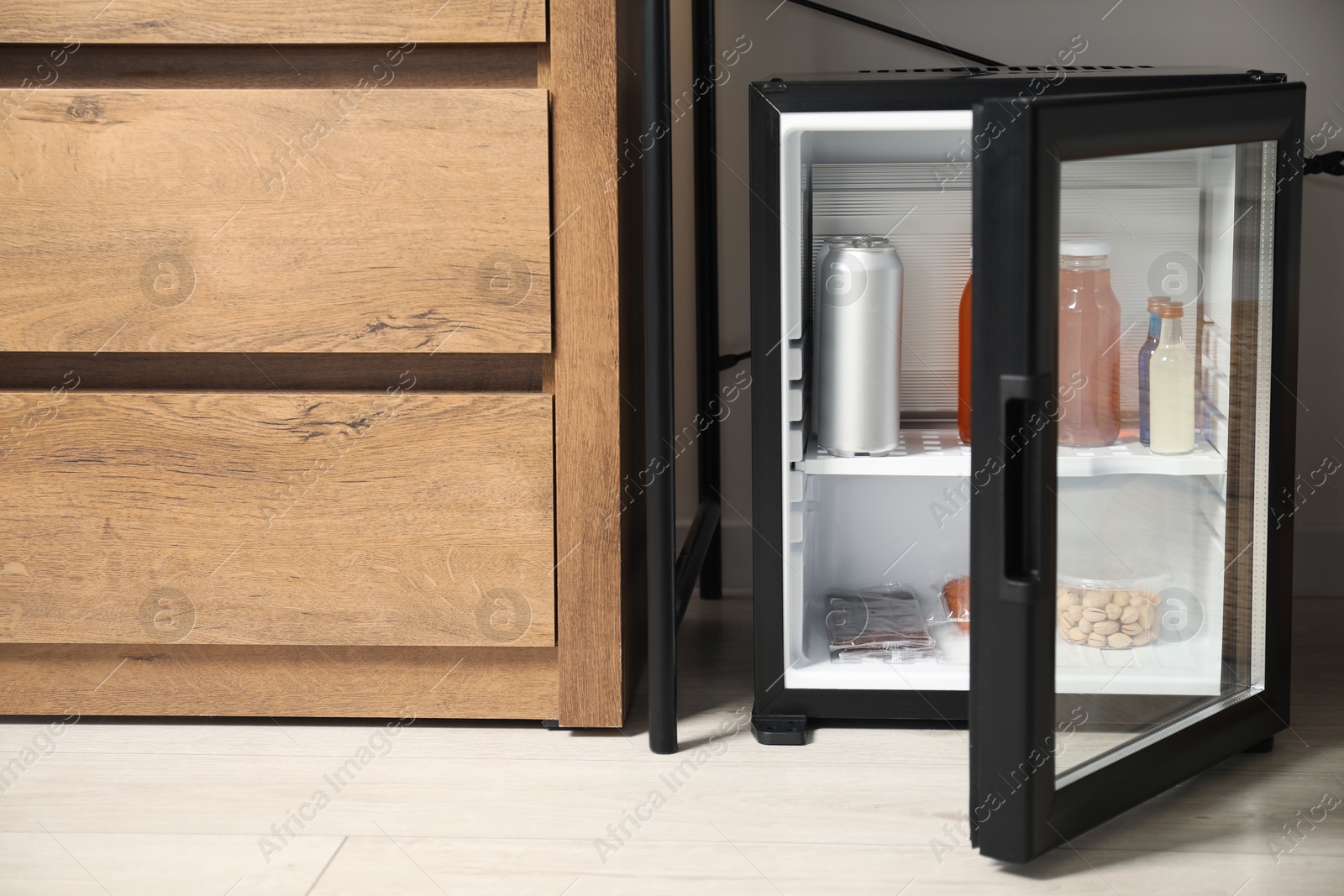 Photo of Mini refrigerator with different drinks and snacks indoors