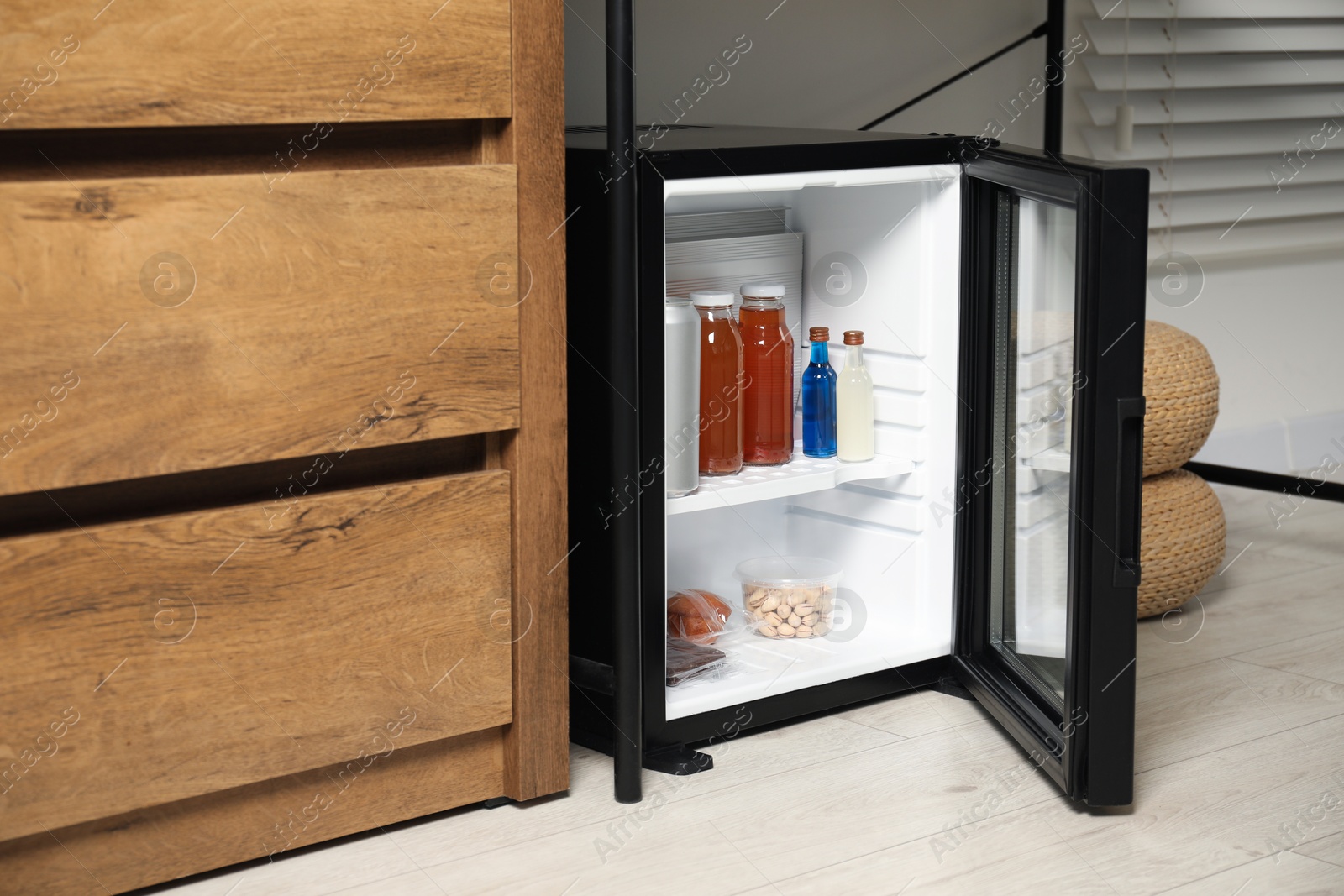 Photo of Mini refrigerator with different drinks and snacks indoors