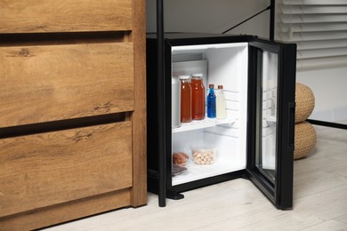 Mini refrigerator with different drinks and snacks indoors