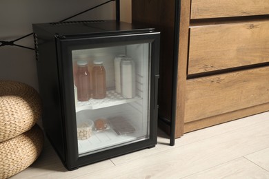 Photo of Mini refrigerator with different drinks and snacks indoors