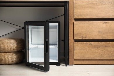 Photo of Empty modern mini refrigerator on floor indoors