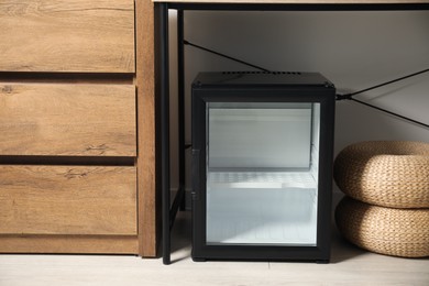 Photo of Empty modern mini refrigerator on floor indoors