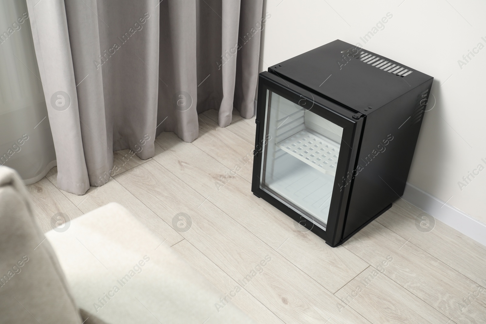 Photo of Empty modern mini refrigerator on floor indoors