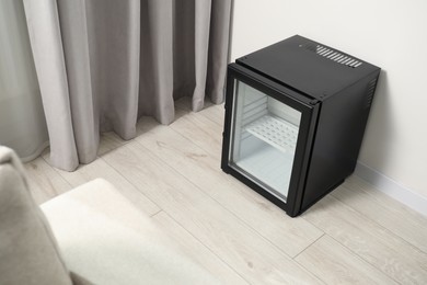 Empty modern mini refrigerator on floor indoors