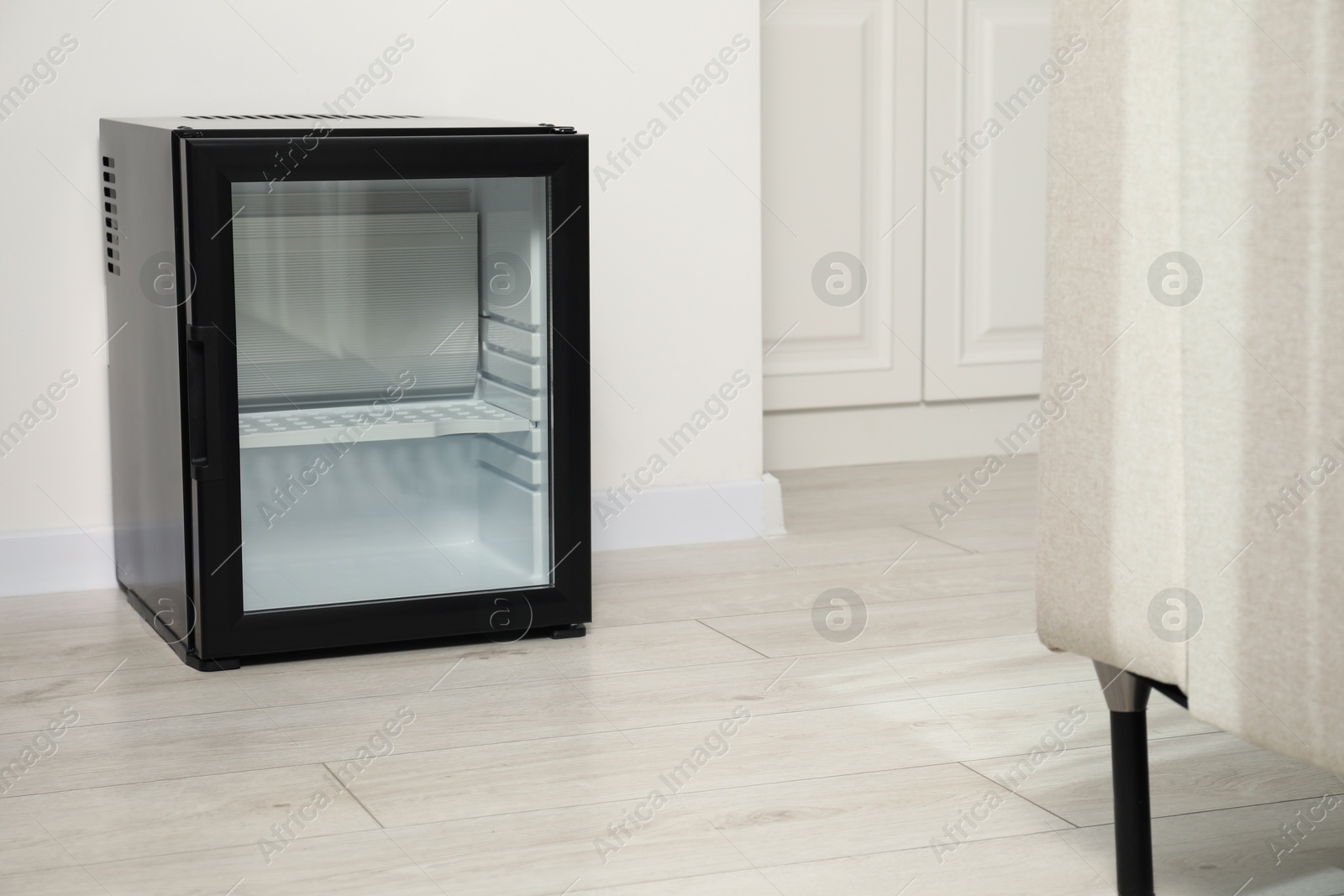 Photo of Empty modern mini refrigerator on floor indoors, space for text