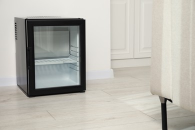 Empty modern mini refrigerator on floor indoors, space for text