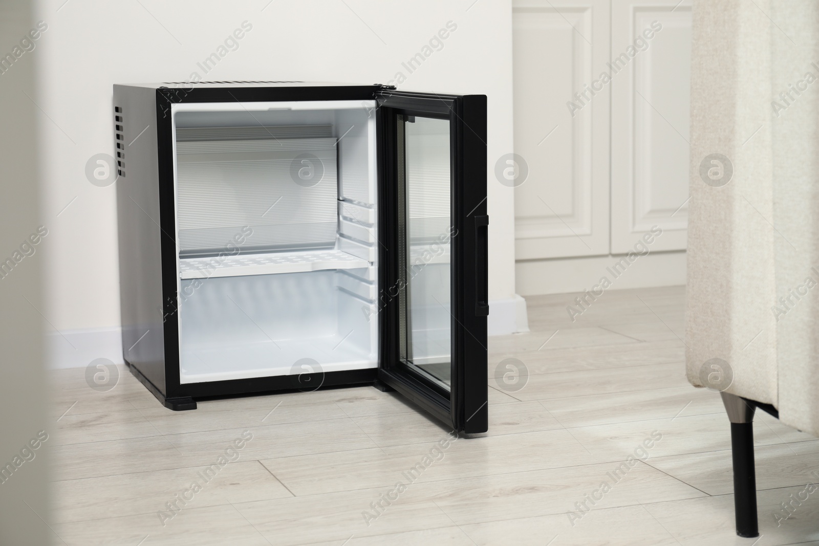 Photo of Empty modern mini refrigerator on floor indoors