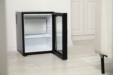 Photo of Empty modern mini refrigerator on floor indoors