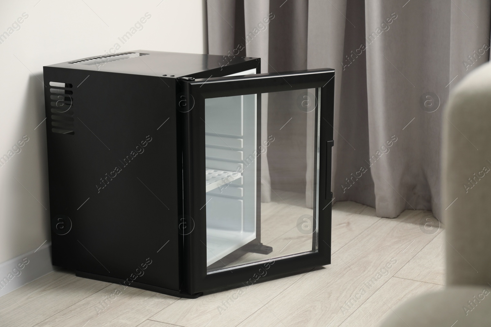 Photo of Empty modern mini refrigerator on floor indoors