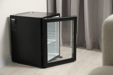 Empty modern mini refrigerator on floor indoors