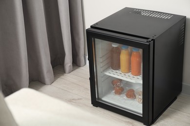 Mini refrigerator with different drinks and snacks indoors