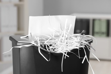 Photo of Destroying sheet of paper with shredder indoors, closeup