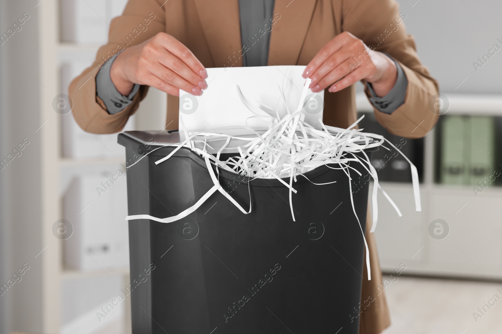 Photo of Woman destroying sheet of paper with shredder in office, closeup