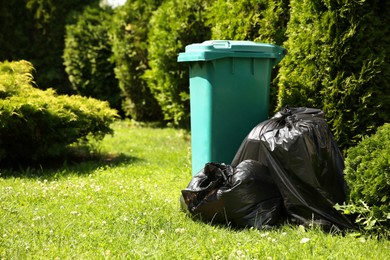 Photo of Trash bags full of garbage near bin outdoors