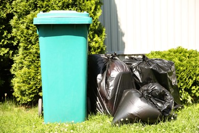 Trash bags full of garbage near bin outdoors