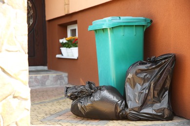 Trash bags full of garbage near bin outdoors