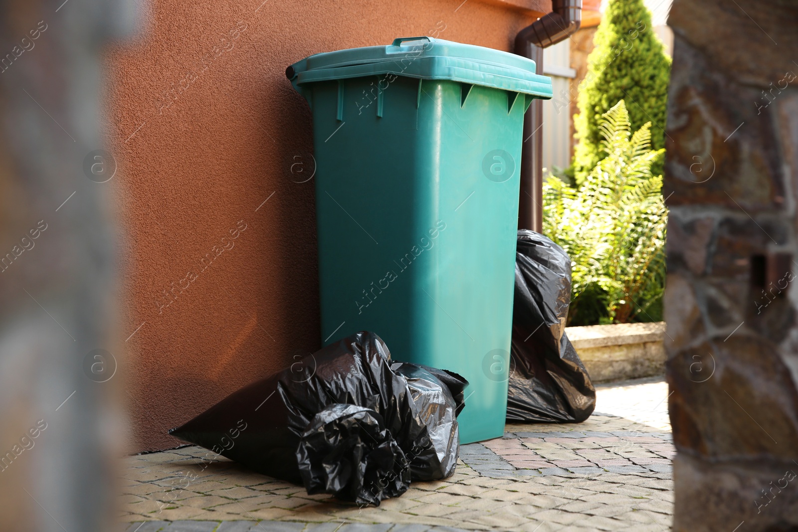 Photo of Trash bags full of garbage near bin outdoors