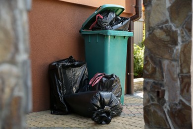 Photo of Trash bags full of garbage near bin outdoors