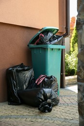 Photo of Trash bags full of garbage near bin outdoors