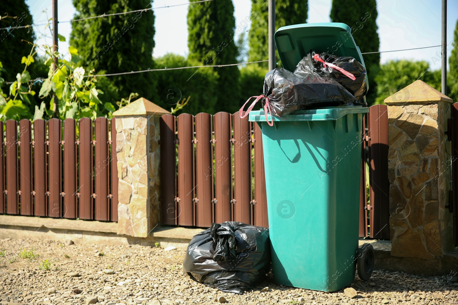 Photo of Trash bags full of garbage and bin outdoors