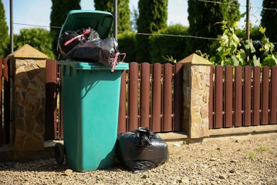 Photo of Trash bags full of garbage and bin outdoors