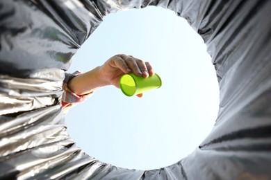 Man throwing garbage into trash bin outdoors, bottom view