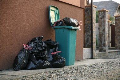 Photo of Trash bags full of garbage near bin outdoors