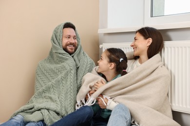 Happy family near heating radiator at home