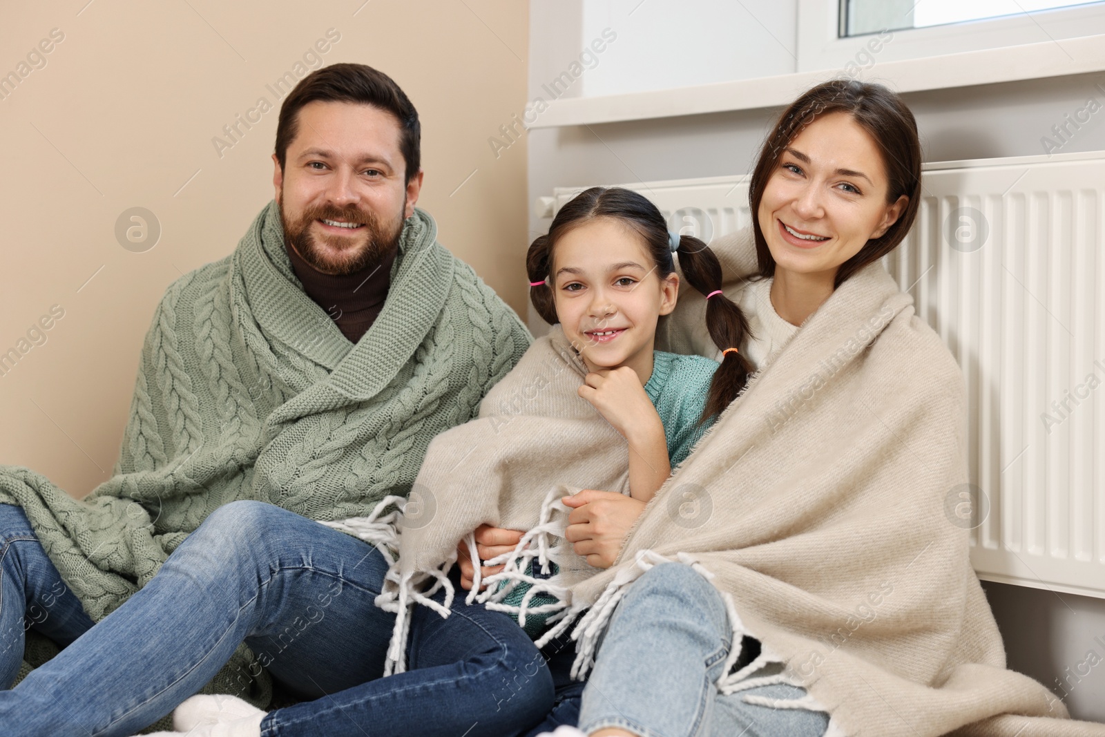 Photo of Happy family near heating radiator at home