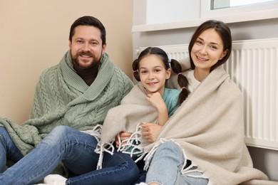 Photo of Happy family near heating radiator at home