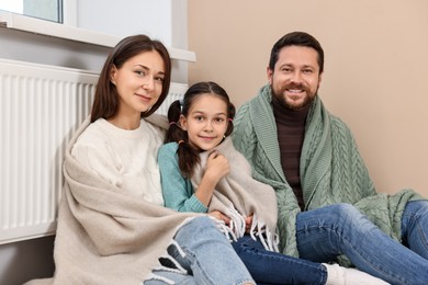 Happy family near heating radiator at home