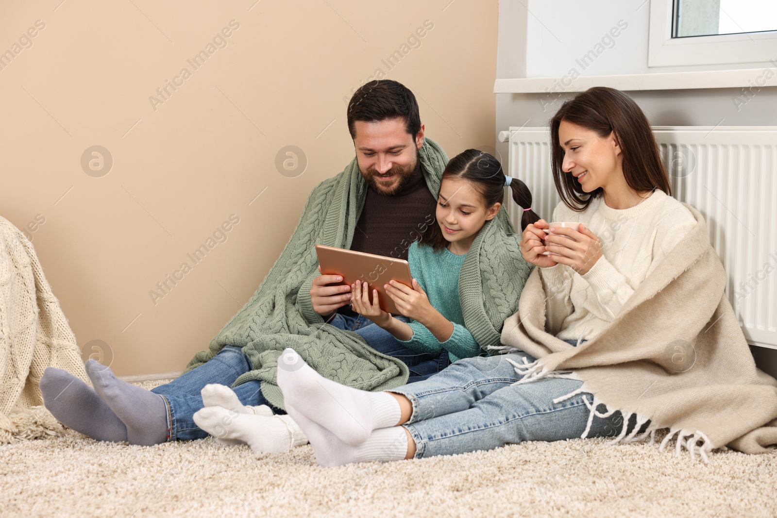 Photo of Happy family with tablet near heating radiator at home