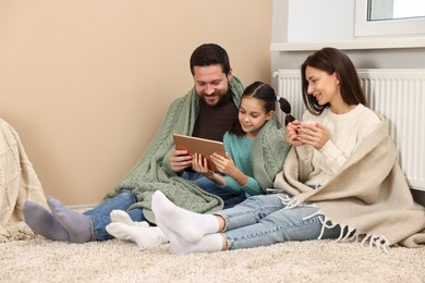 Happy family with tablet near heating radiator at home