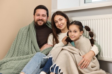 Happy family near heating radiator at home