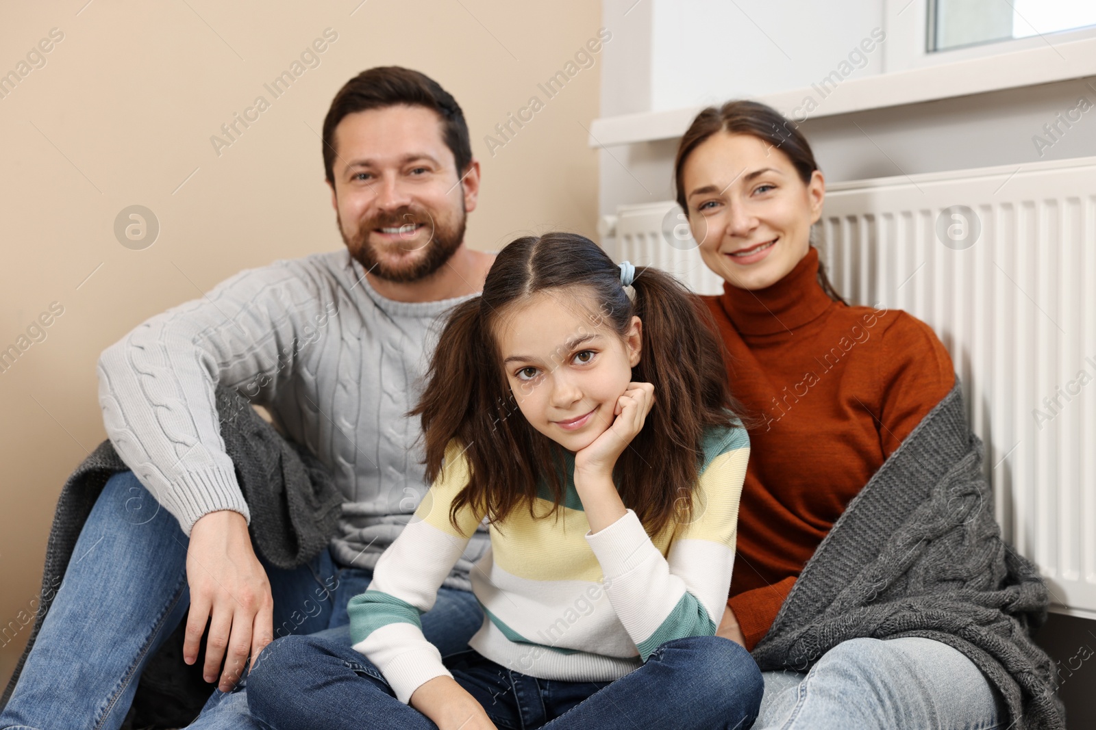 Photo of Happy family near heating radiator at home