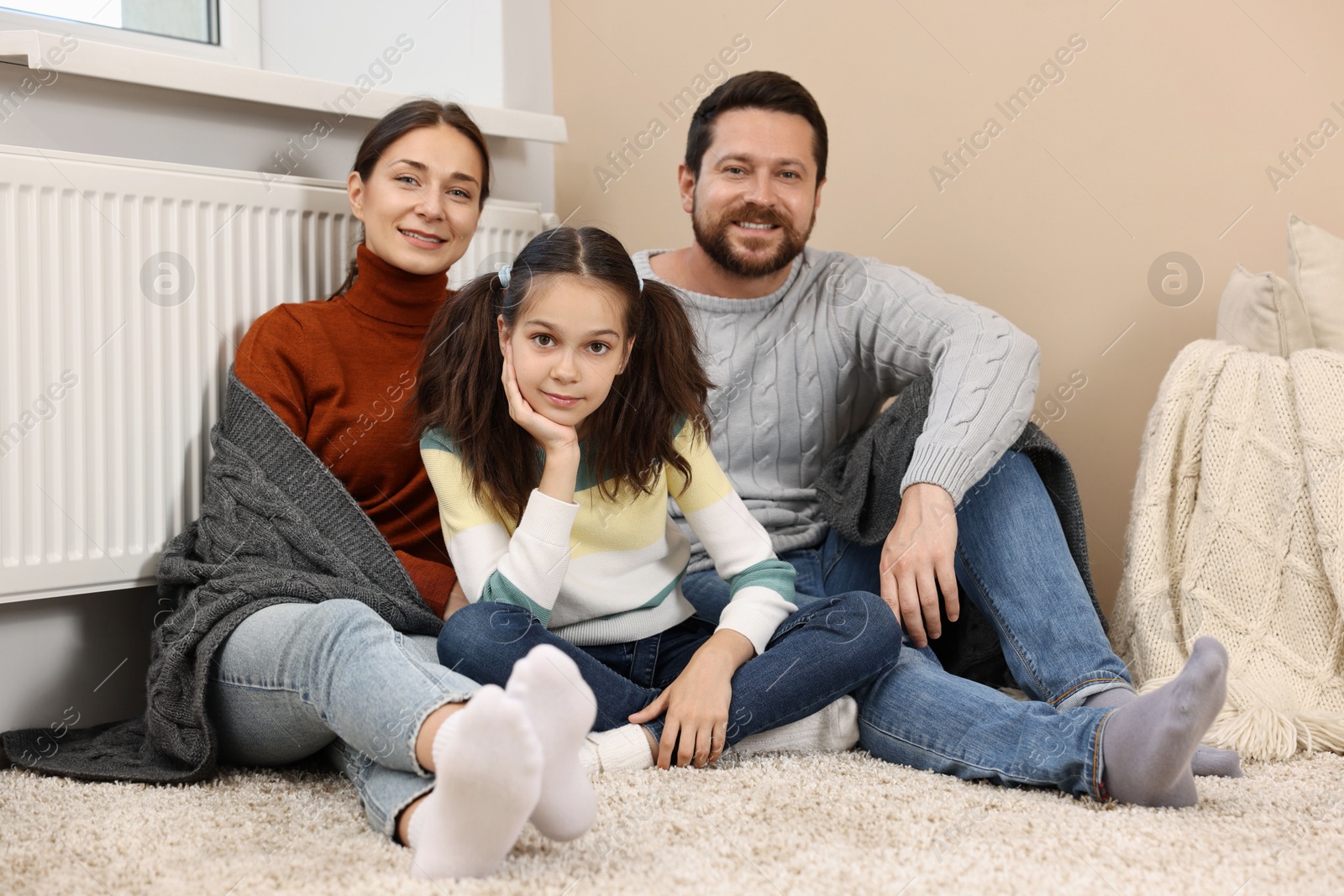 Photo of Happy family near heating radiator at home