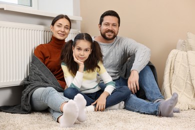 Happy family near heating radiator at home