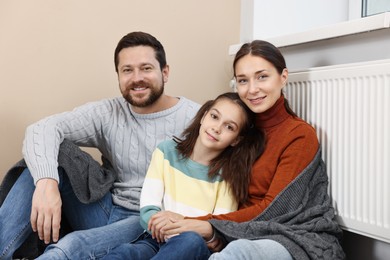 Happy family near heating radiator at home