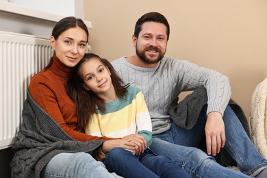 Photo of Happy family near heating radiator at home