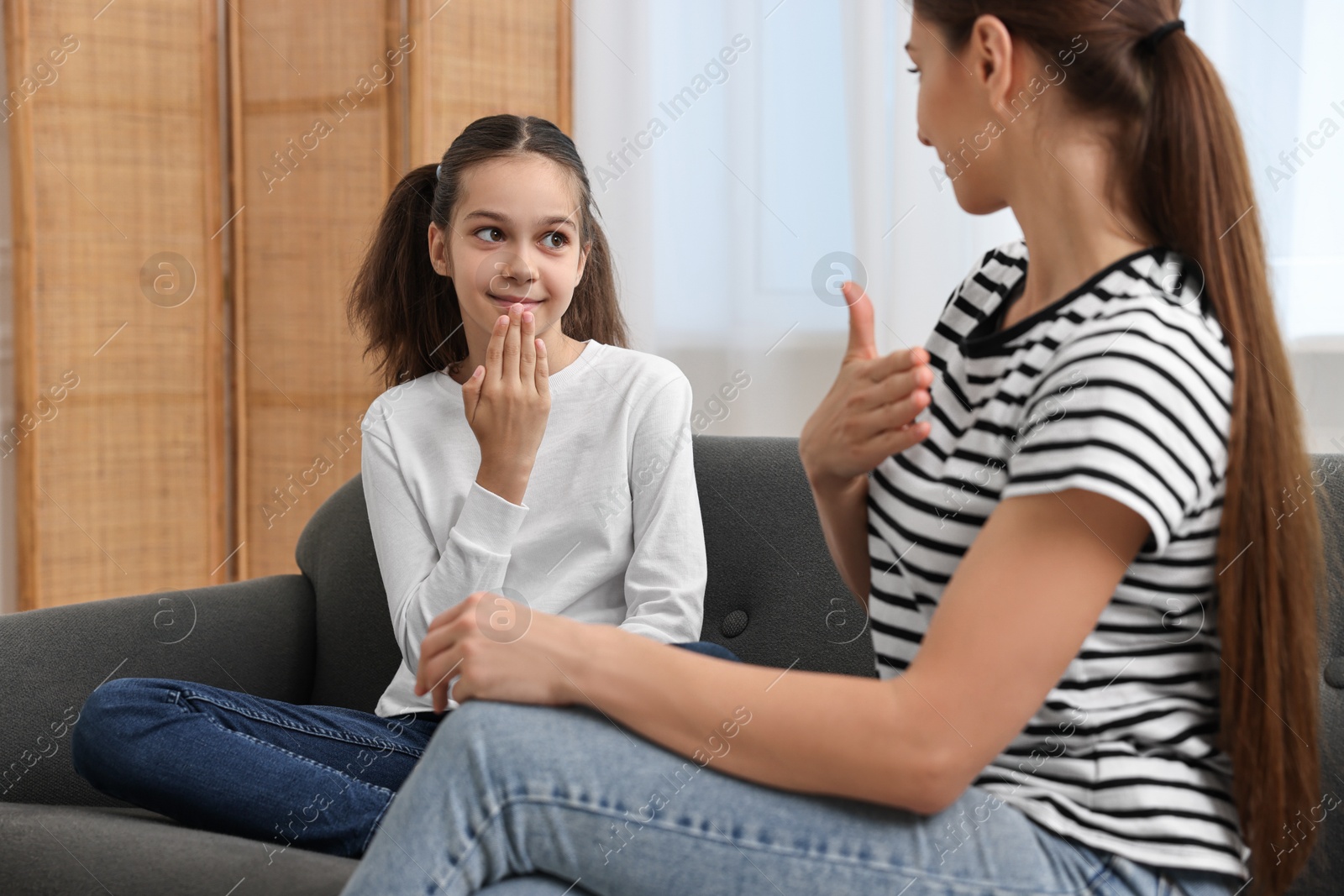 Photo of Woman and her daughter using sign language for communication at home