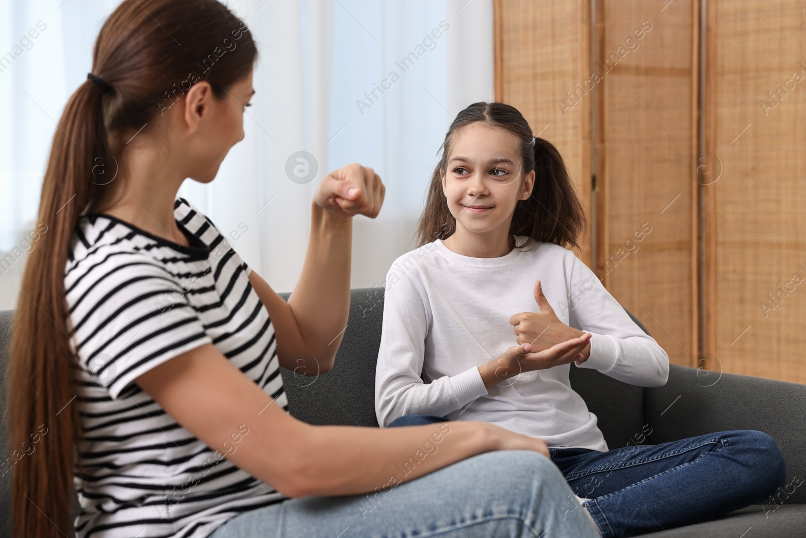 Photo of Woman and her daughter using sign language for communication at home