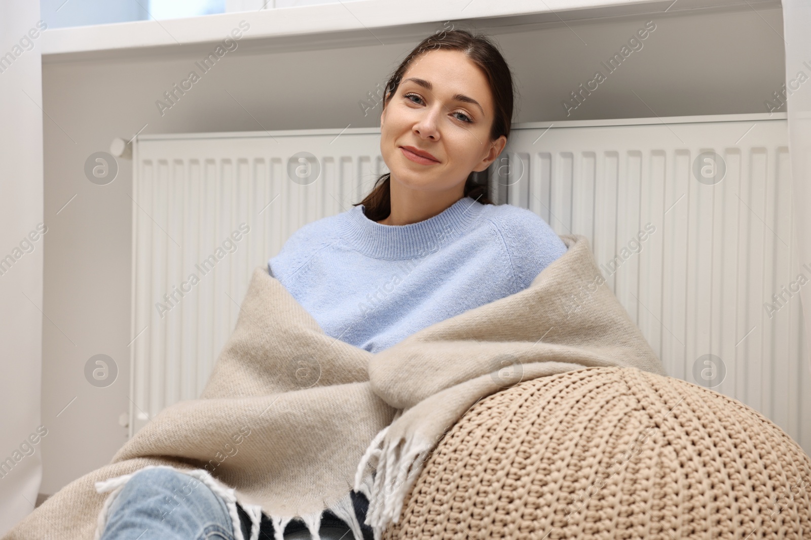 Photo of Woman with blanket warming heating radiator at home