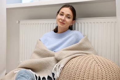 Photo of Woman with blanket warming heating radiator at home