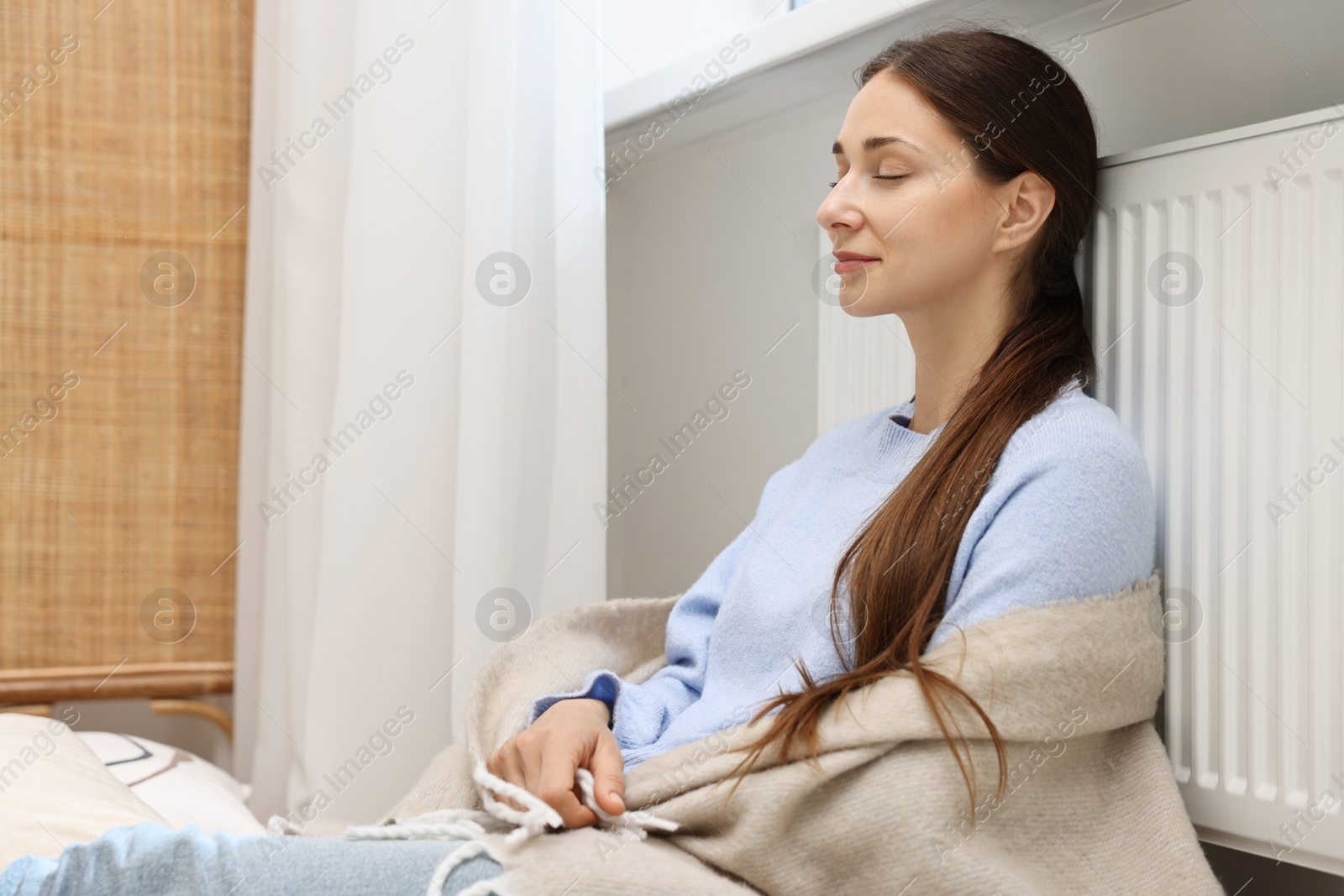 Photo of Woman with blanket warming heating radiator at home