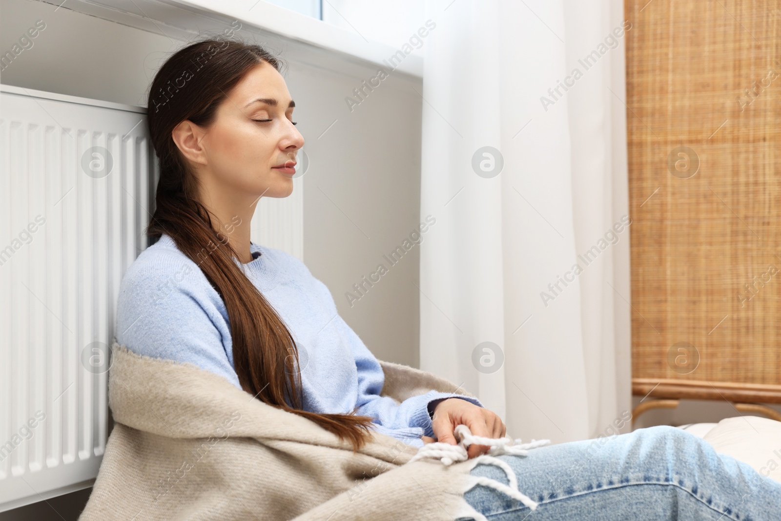 Photo of Woman with blanket warming heating radiator at home