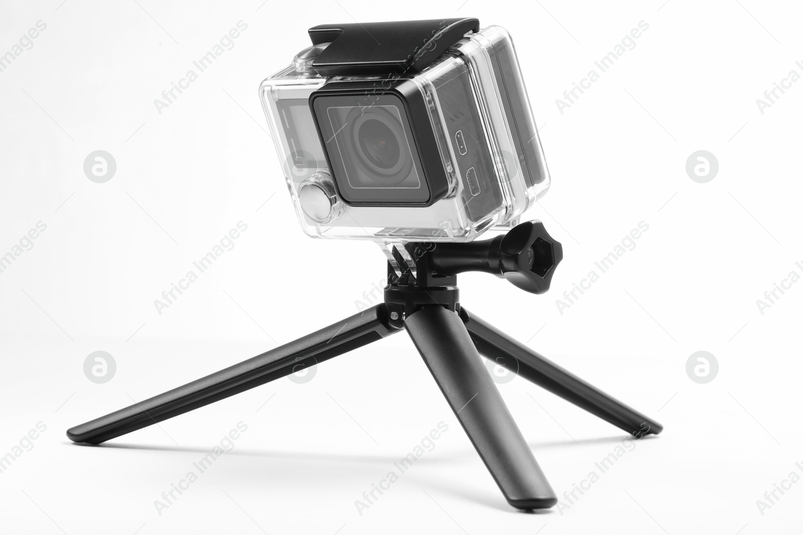 Photo of Modern action camera and tripod ono white background