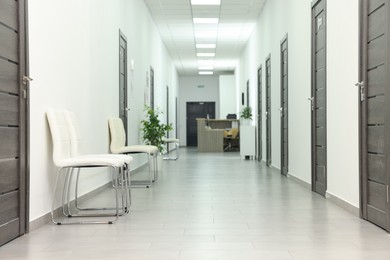 Empty hospital corridor with chairs and doors