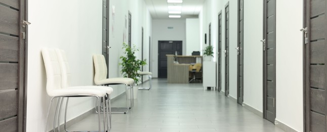 Empty hospital corridor with chairs and doors